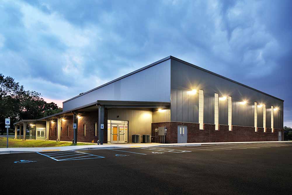 Exterior of large warehouse gym building at night.