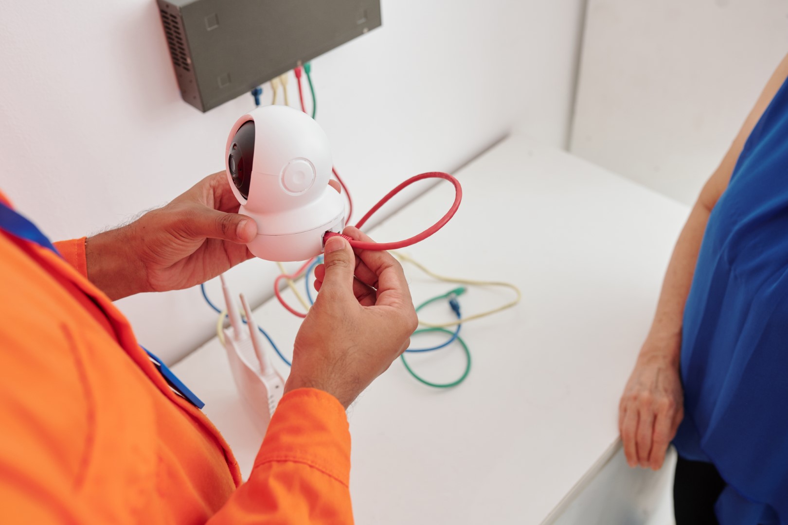 A close-up view of a man’s hands installing wired security cameras in a home