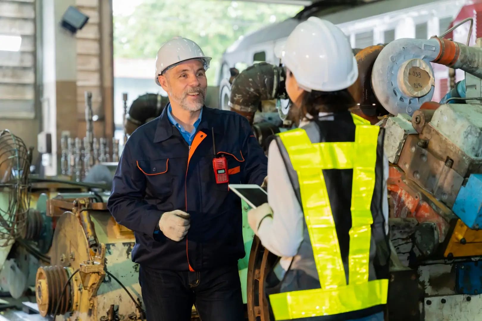 A male supervisor checking the work of a female electrical worker.