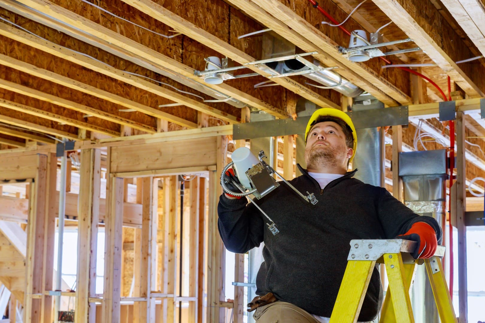 An electrician installing light bulbs in a newly built home.