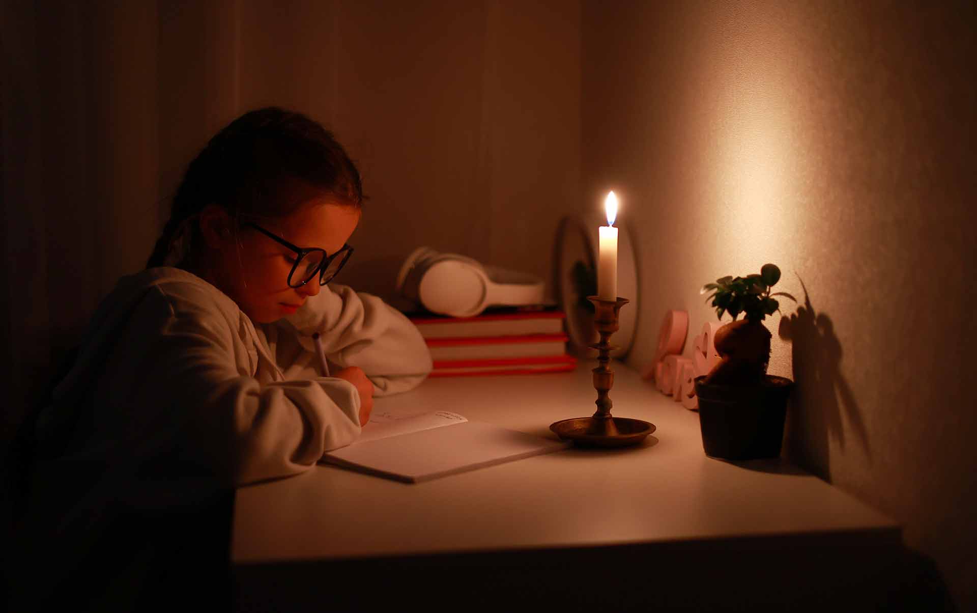 A girl continues reading with candle light during blackout.