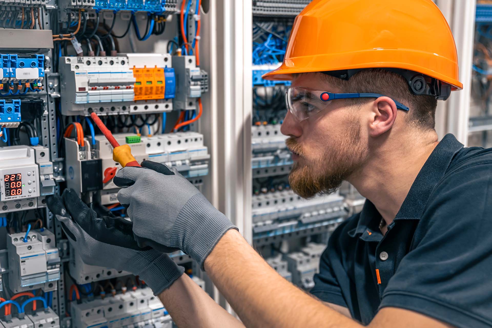 A male electrician is fixing a switchboard.