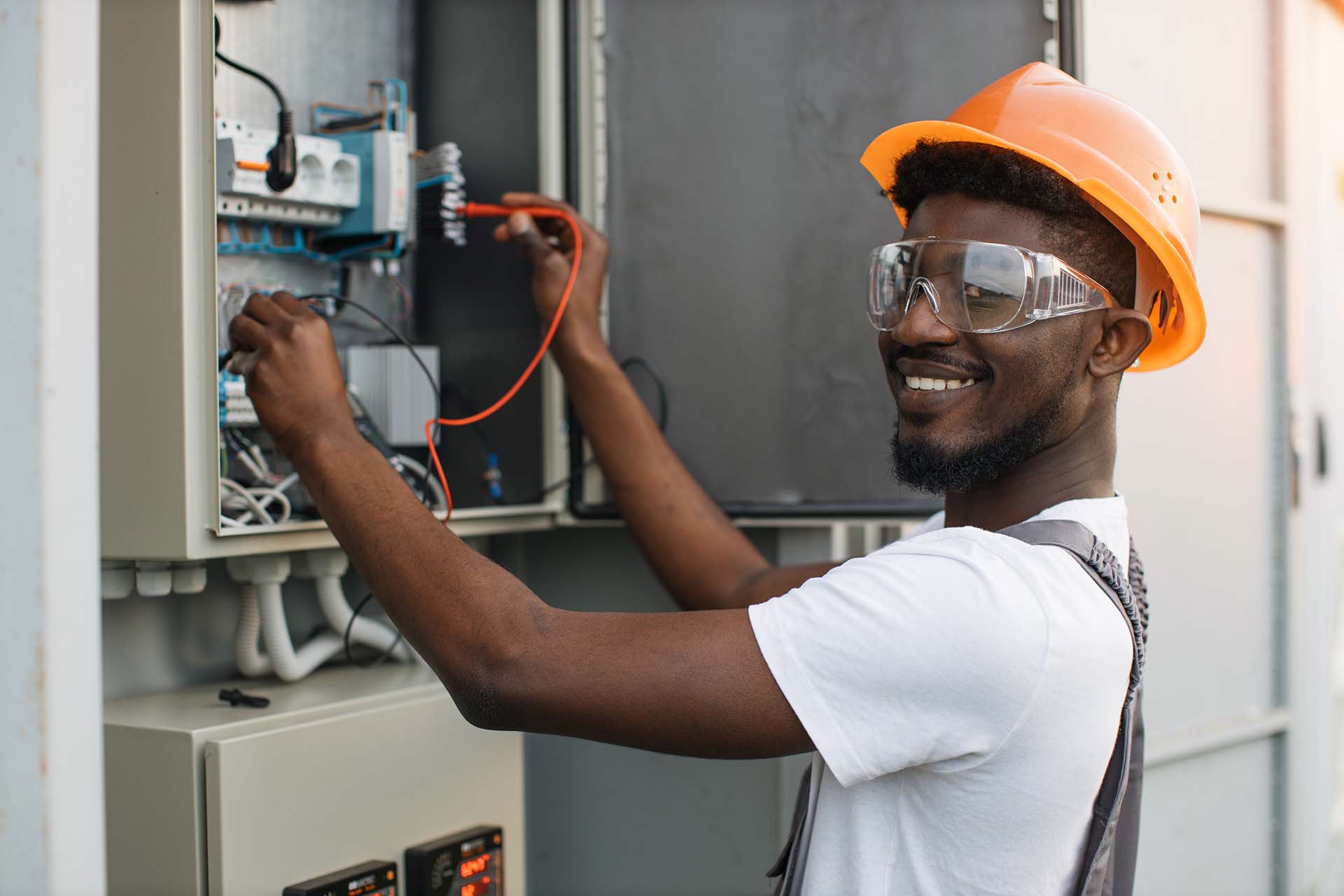 A repairman wearing a helmet checks the cable in the power transformer.