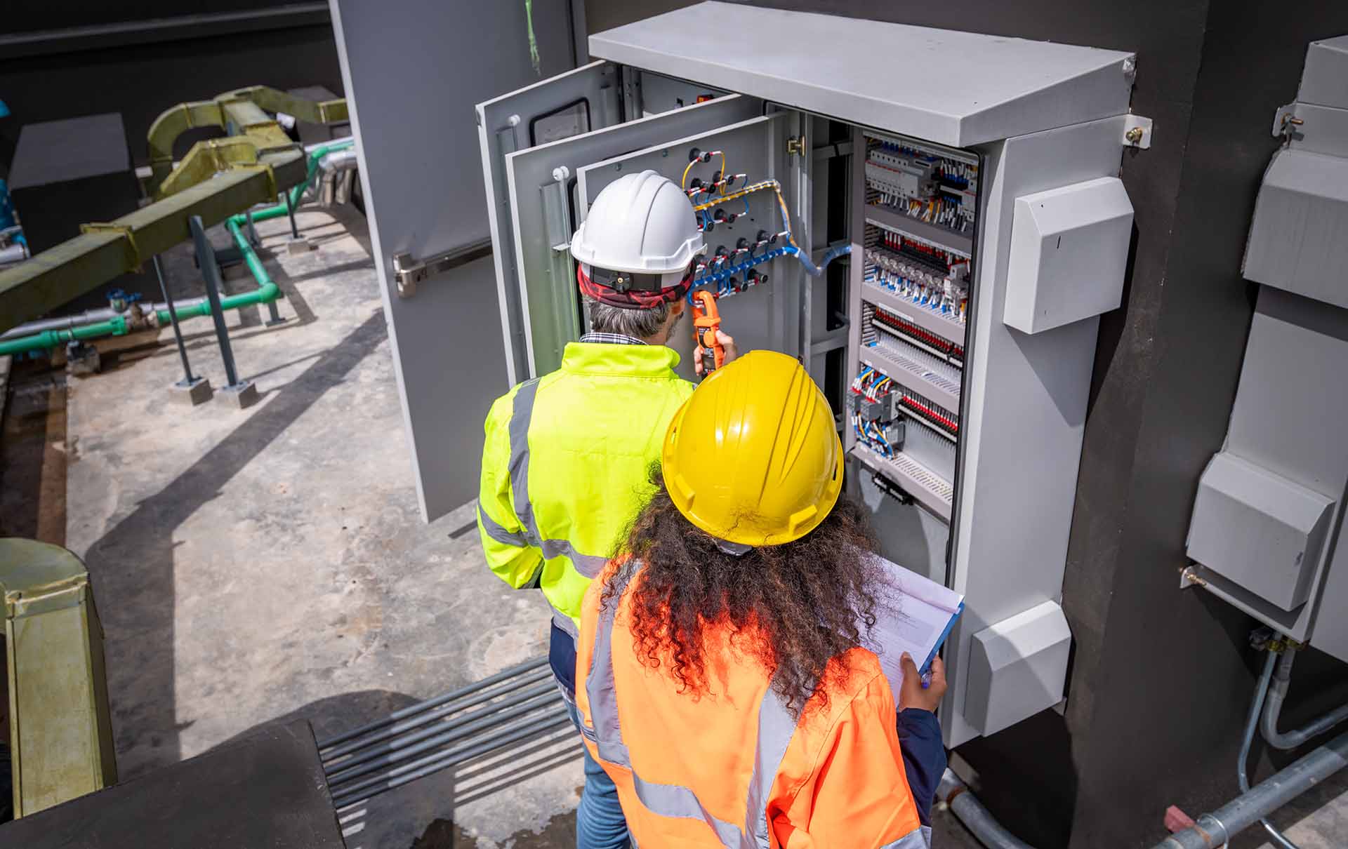 Engineers wearing safety uniforms are inspecting a MDB panel.