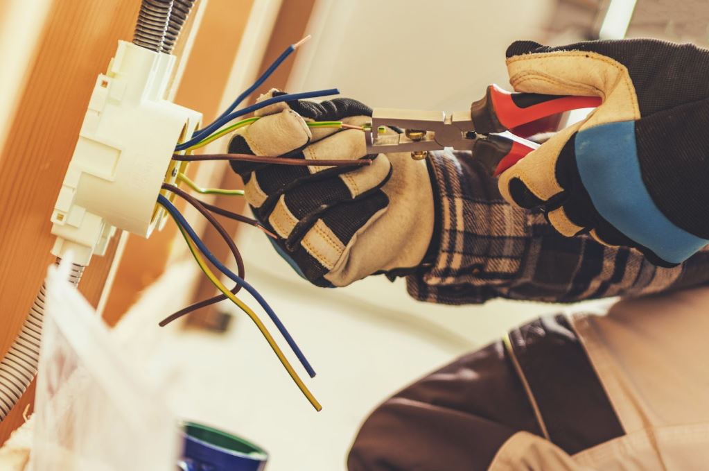 Man in gloves working with exposed wires.