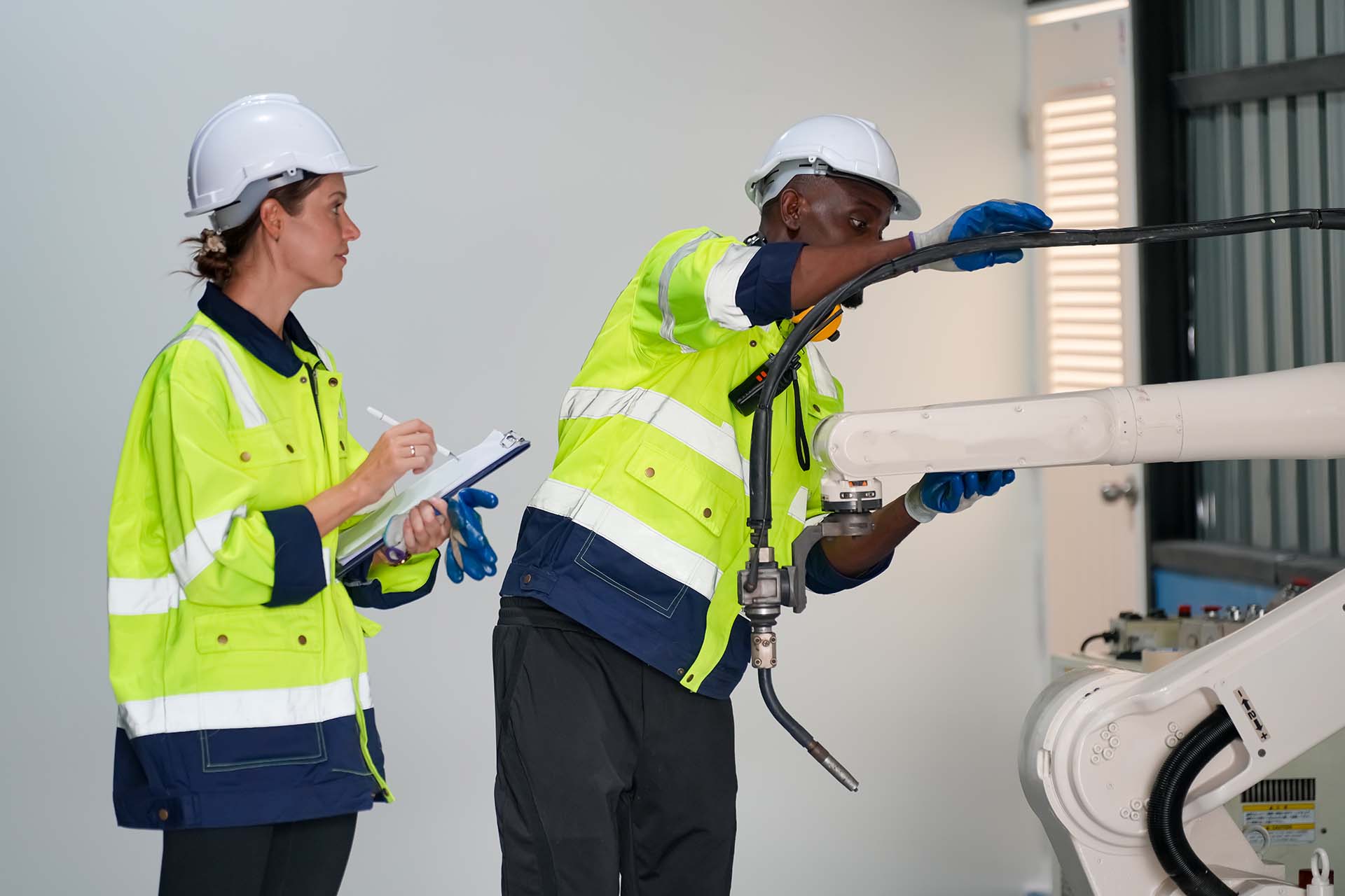 Two electricians are checking a robot machine.