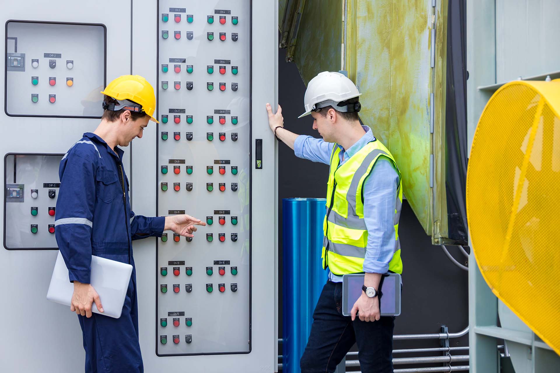 Two male electrical engineers are working in a control room.