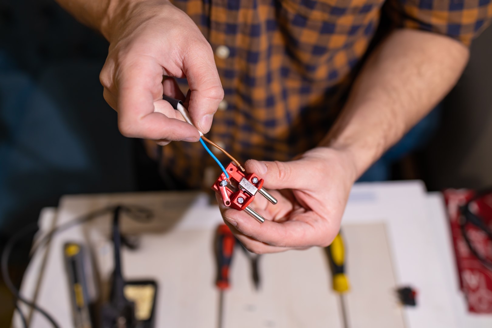 A man’s hands use tools to work with electrical wiring.