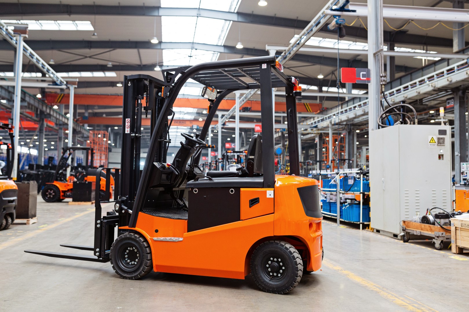 An orange and black forklift parked in an industrial garage.