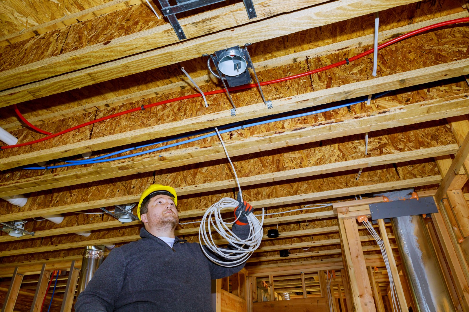 Two electrical engineers wearing white hard hats are working on installing wiring.