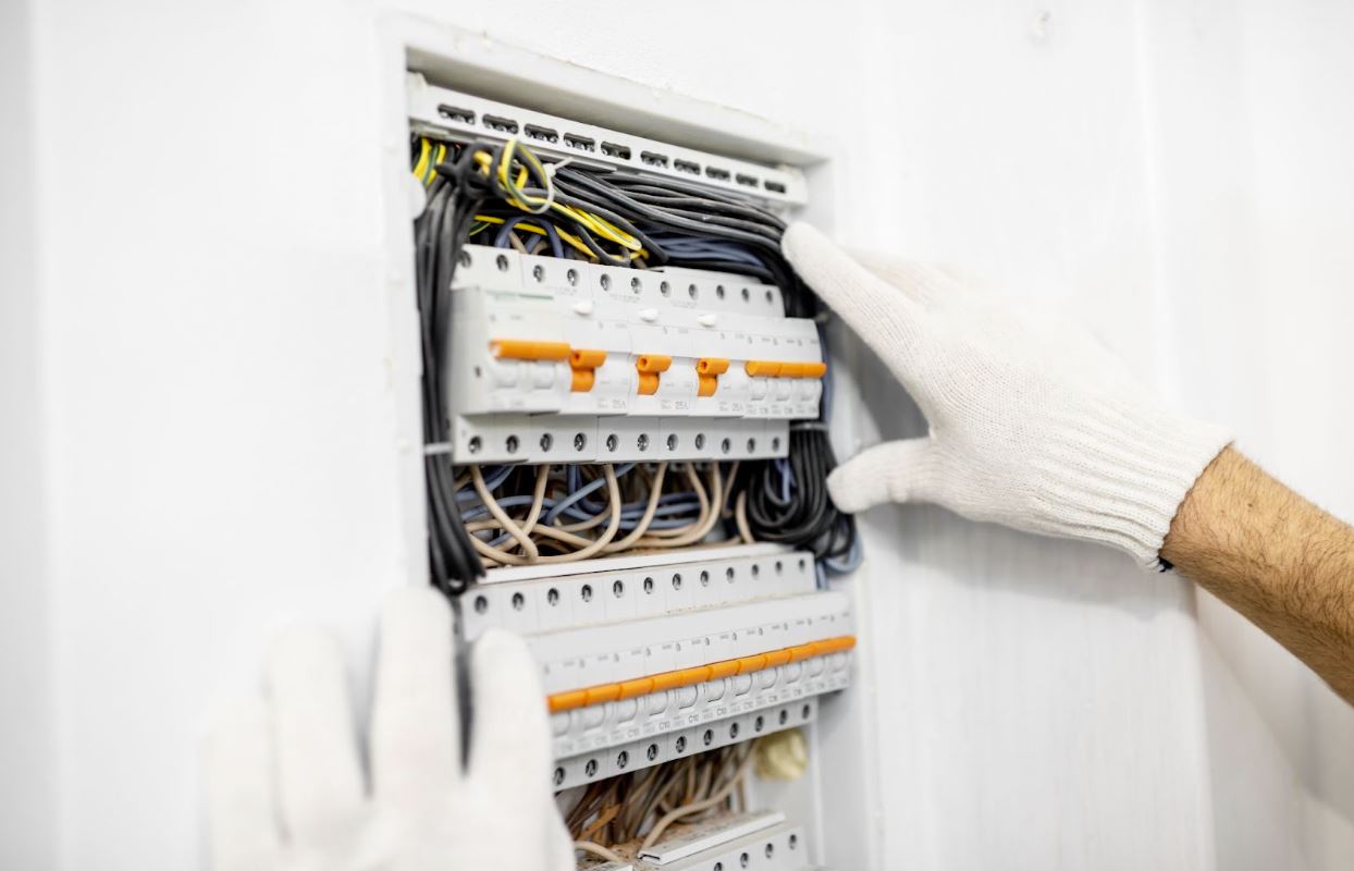 Gloved man working with an electrical box.