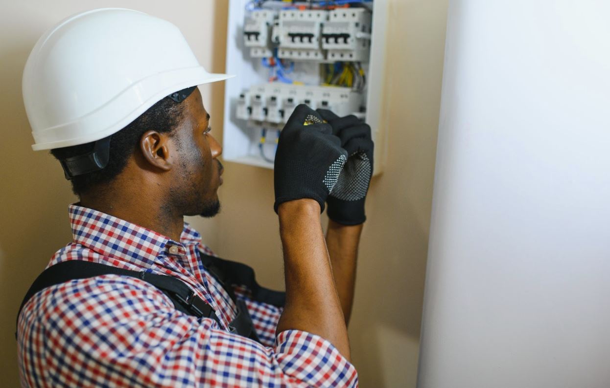 Man in a hard hat working on an electrical panel.